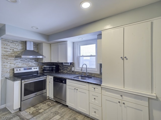 kitchen with white cabinetry, appliances with stainless steel finishes, decorative backsplash, sink, and wall chimney exhaust hood