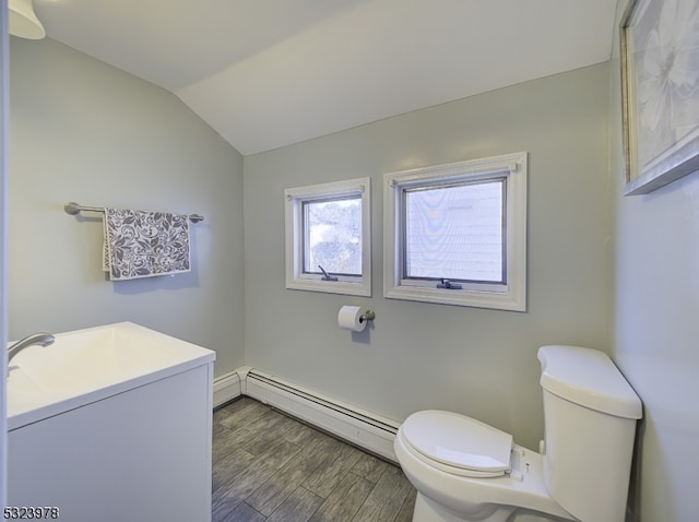 bathroom with vanity, hardwood / wood-style floors, vaulted ceiling, a baseboard heating unit, and toilet