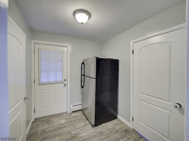 interior space with light hardwood / wood-style floors, stainless steel fridge, and a baseboard radiator