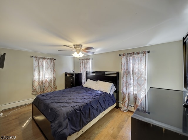 bedroom with hardwood / wood-style flooring, baseboard heating, and ceiling fan