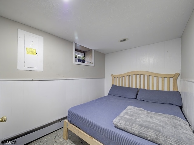 bedroom featuring electric panel, wood walls, and a baseboard radiator