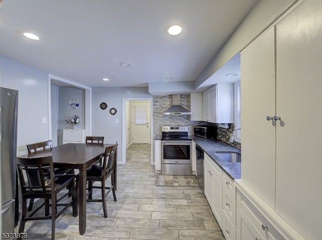 kitchen featuring backsplash, appliances with stainless steel finishes, sink, white cabinets, and wall chimney exhaust hood