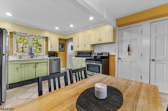 kitchen with stainless steel appliances, green cabinets, light tile patterned floors, beam ceiling, and sink