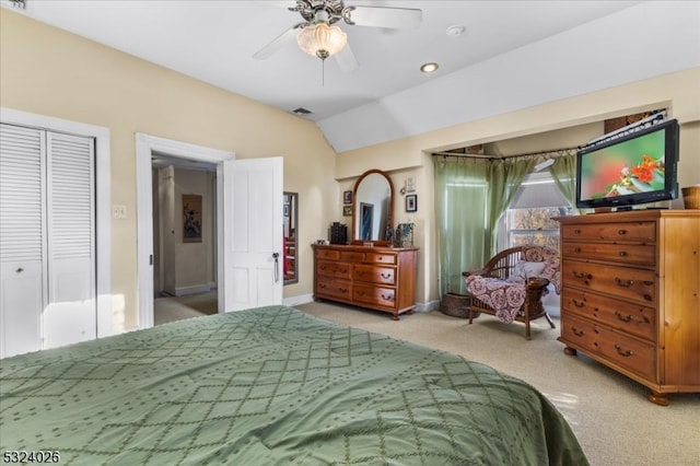 bedroom with ceiling fan, a closet, vaulted ceiling, and light colored carpet