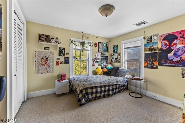 carpeted bedroom with multiple windows and a closet