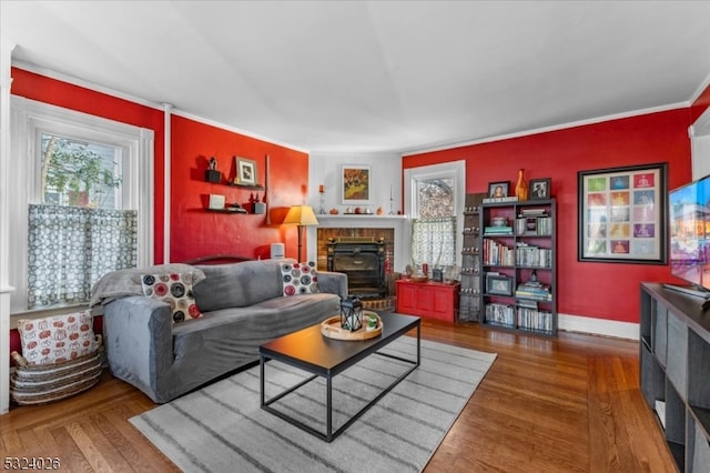 living room with a brick fireplace, hardwood / wood-style floors, and crown molding