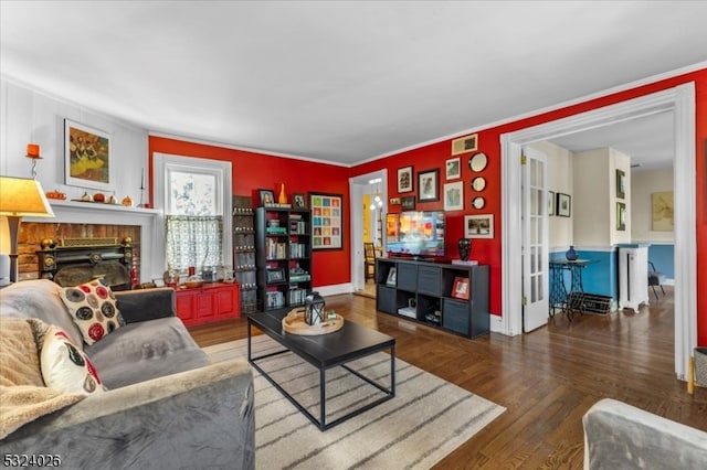 living room with a brick fireplace, ornamental molding, and hardwood / wood-style flooring