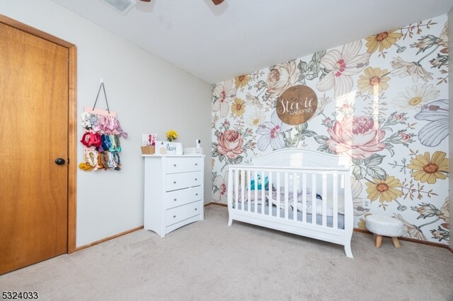 bedroom with carpet, a nursery area, and ceiling fan