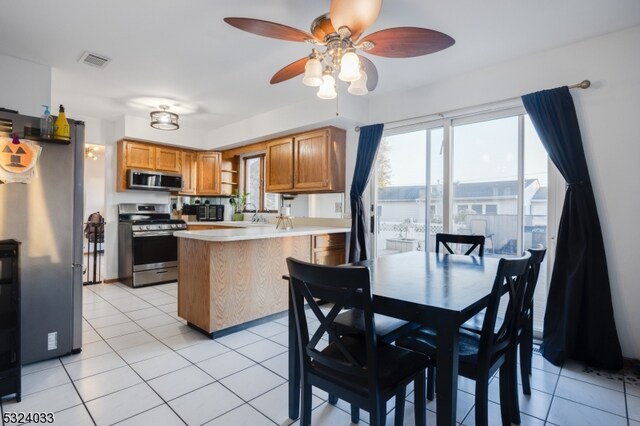 kitchen with kitchen peninsula, light tile patterned floors, ceiling fan, and stainless steel appliances