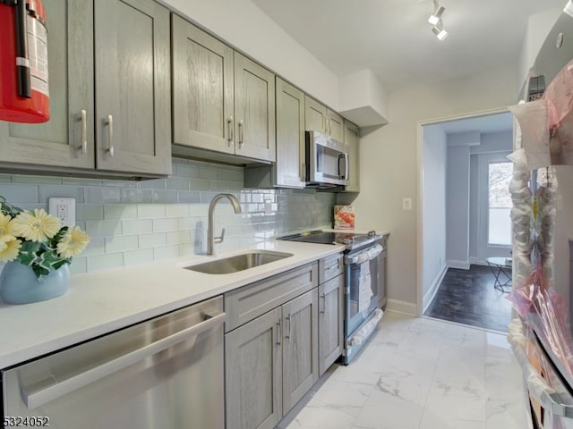 kitchen with decorative backsplash, appliances with stainless steel finishes, sink, and track lighting