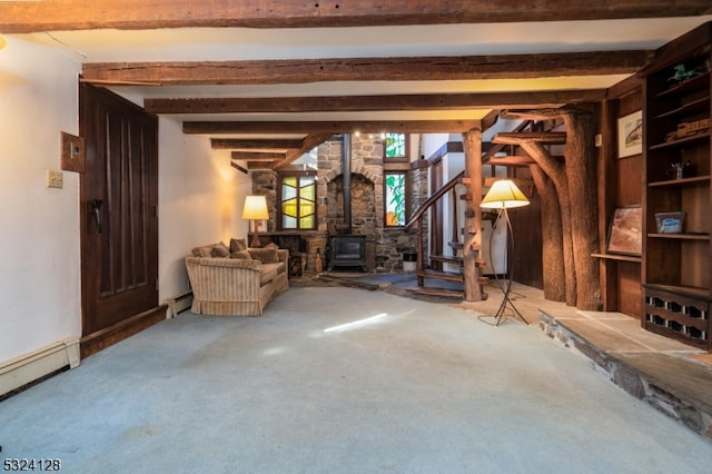 unfurnished living room featuring baseboard heating, beam ceiling, carpet flooring, and a wood stove