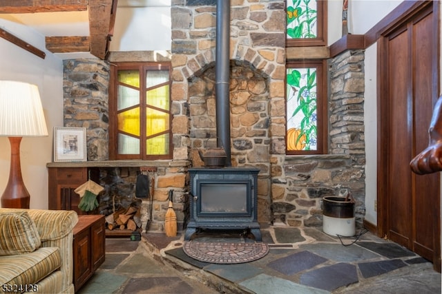 living room featuring a wealth of natural light, a wood stove, and beam ceiling