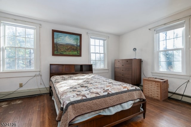 bedroom with baseboard heating, multiple windows, and dark hardwood / wood-style flooring