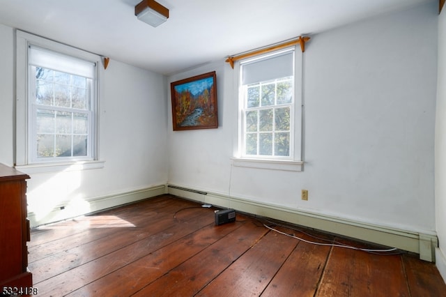 unfurnished room featuring a baseboard heating unit, dark wood-type flooring, and a healthy amount of sunlight