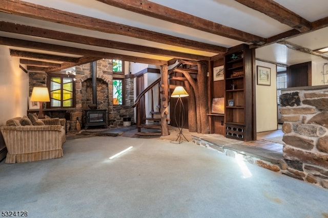 unfurnished living room featuring beamed ceiling, a wood stove, and light colored carpet