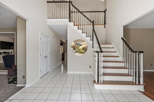 staircase with baseboards, a high ceiling, and tile patterned flooring