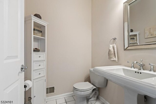 half bathroom with baseboards, visible vents, a sink, tile patterned flooring, and toilet