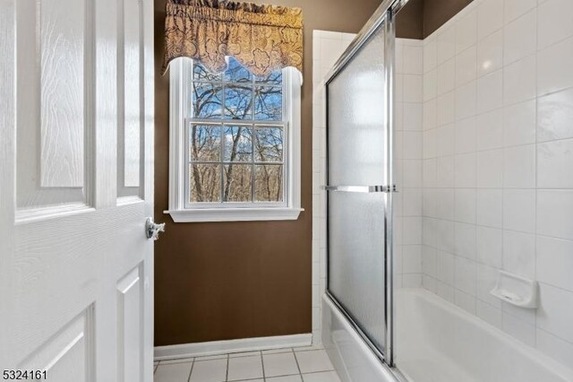 bathroom with tile patterned floors, baseboards, and shower / bath combination with glass door