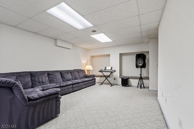 living room featuring a drop ceiling, carpet flooring, and baseboards