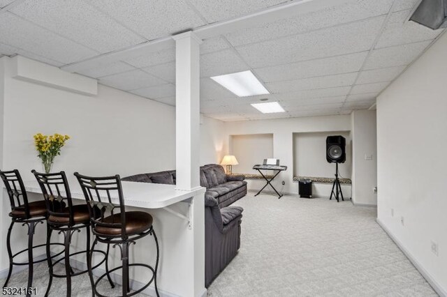 living area featuring carpet flooring and a paneled ceiling