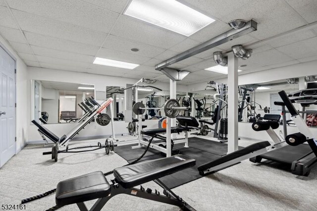 exercise room featuring baseboards and a paneled ceiling