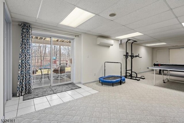 workout room with a wall mounted air conditioner, baseboards, and a paneled ceiling