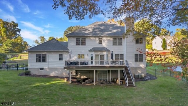 rear view of house with a lawn, fence, stairway, a wooden deck, and a chimney