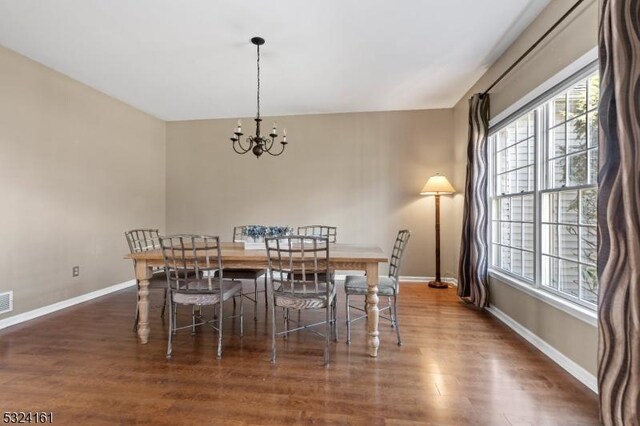 dining room featuring visible vents, an inviting chandelier, baseboards, and wood finished floors