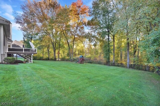 view of yard with stairway, fence, a wooden deck, and a playground