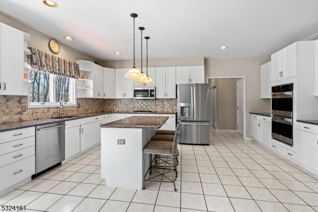 kitchen with light tile patterned floors, a kitchen island, a breakfast bar, open shelves, and appliances with stainless steel finishes