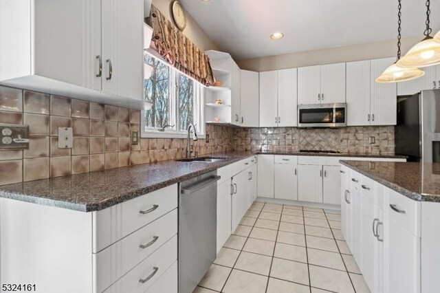 kitchen featuring a sink, stainless steel appliances, white cabinets, light tile patterned floors, and decorative backsplash