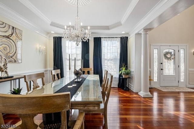 dining area featuring ornamental molding, a tray ceiling, dark hardwood / wood-style flooring, and decorative columns