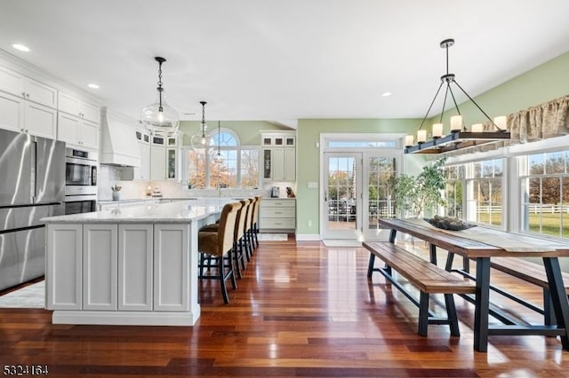 kitchen featuring white cabinetry, stainless steel appliances, hanging light fixtures, and a kitchen island