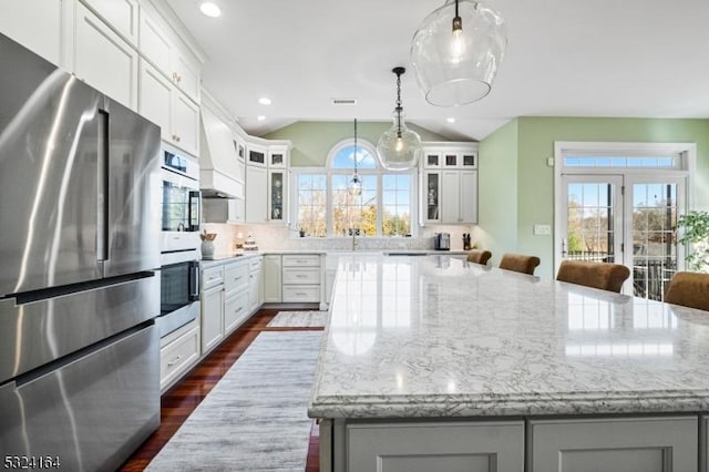 kitchen with hanging light fixtures, white cabinetry, a large island, and stainless steel fridge