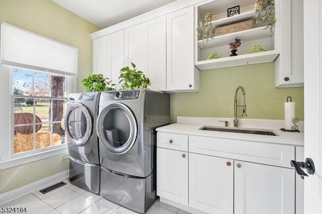 laundry room with cabinets, washing machine and dryer, sink, and light tile patterned flooring