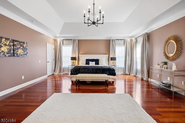 bedroom with multiple windows, dark hardwood / wood-style floors, a notable chandelier, and a tray ceiling