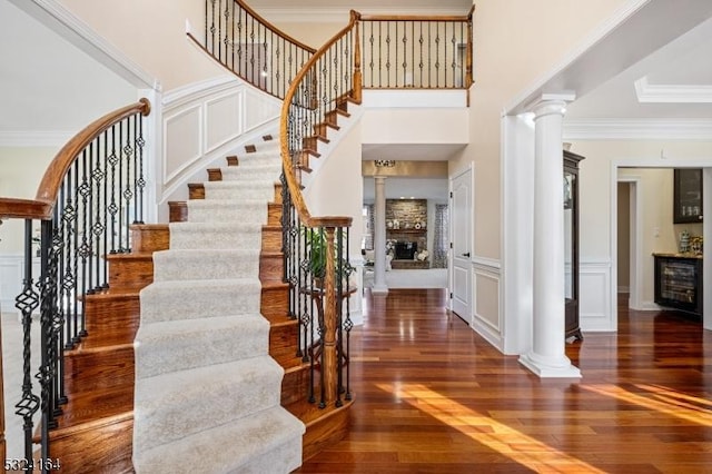 foyer featuring decorative columns, ornamental molding, and dark hardwood / wood-style flooring