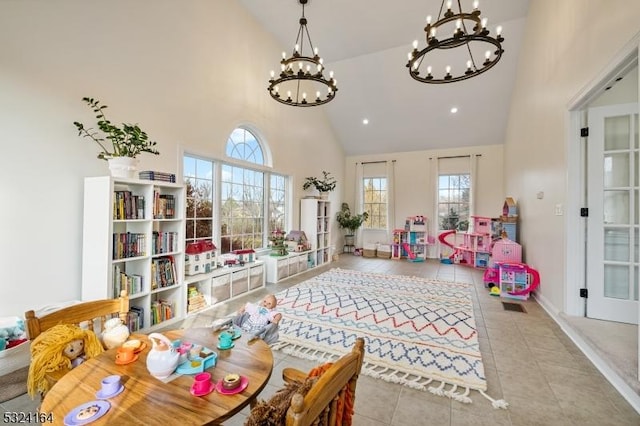 recreation room featuring an inviting chandelier, light tile patterned floors, and high vaulted ceiling