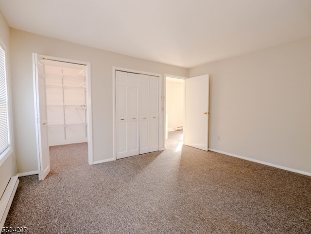 unfurnished bedroom with a walk in closet, carpet floors, and a baseboard heating unit