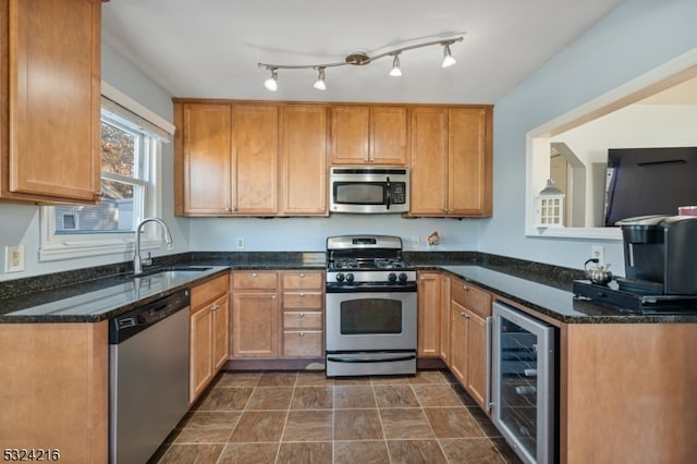 kitchen with appliances with stainless steel finishes, sink, beverage cooler, and dark stone countertops