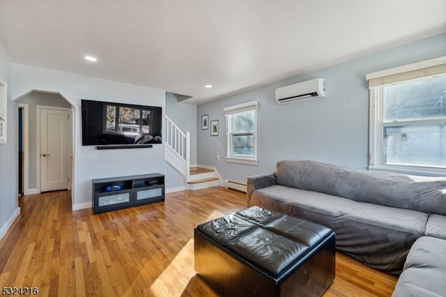 living room featuring hardwood / wood-style flooring, a wall mounted air conditioner, and a baseboard heating unit