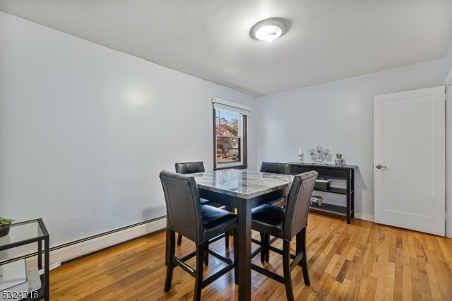 dining area featuring a baseboard heating unit and light hardwood / wood-style flooring