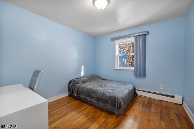 bedroom with a baseboard heating unit and hardwood / wood-style floors