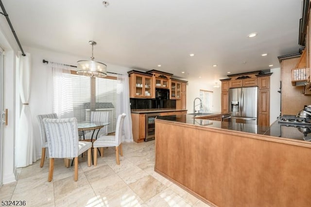 kitchen featuring brown cabinetry, stainless steel fridge with ice dispenser, a sink, glass insert cabinets, and a chandelier