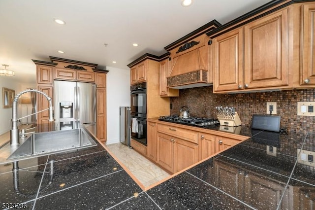 kitchen with premium range hood, stainless steel refrigerator with ice dispenser, gas stovetop, dobule oven black, and a sink