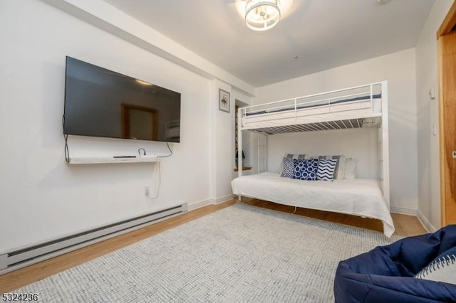 bedroom featuring wood finished floors, baseboards, and a baseboard radiator