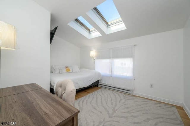 bedroom featuring vaulted ceiling with skylight, wood finished floors, baseboards, and baseboard heating