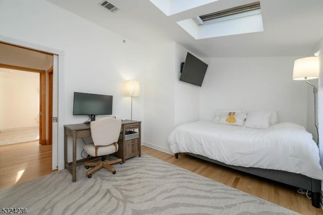 bedroom featuring visible vents, a skylight, and wood finished floors