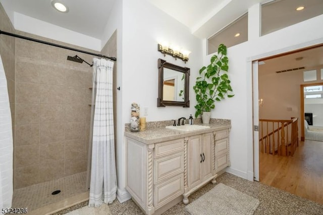 full bath with a tile shower, recessed lighting, and vanity