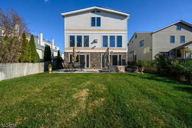 back of property with fence, a yard, a patio area, and stone siding